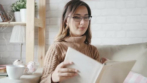 Woman Reading Book Relaxing on Sofa Indoors