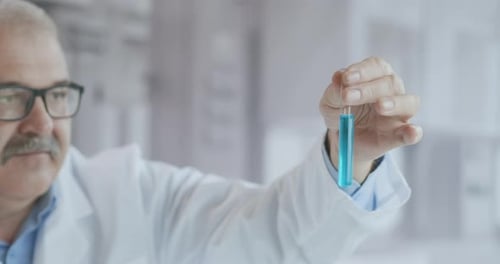 Senior Scientist Examining Test Tube in Bright Lab