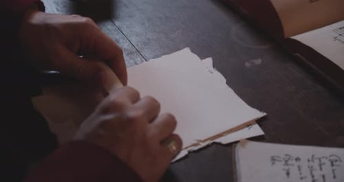 As mãos de uma pessoa rolando uma carta e a selam com um carimbo de cera vermelha