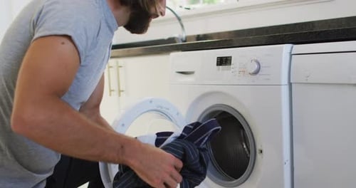 Man Loading Dirty Clothes Into Washing Machine