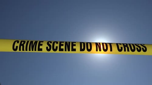 Crime Scene Tape Blocking Entry Against Blue Sky