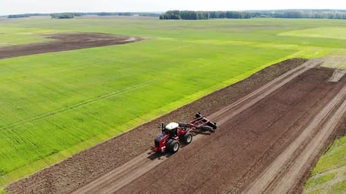 Red Harvester Drives Across Field and Plows Earth