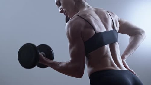 Muscular Woman Lifting Dumbbell During Bicep Curl Exercise