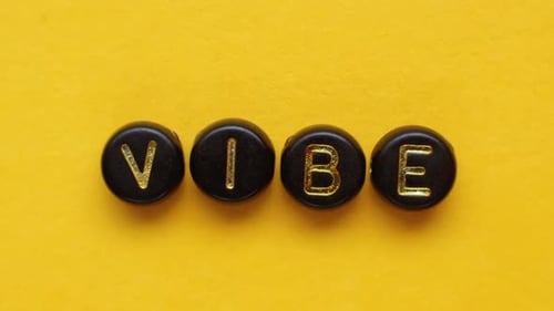 Vibe Spelled Out with Beads on Yellow Background