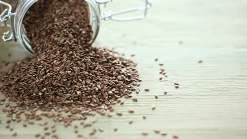 Flax Seeds Being Poured onto Wood Table