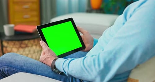 Velho adulto em casa usa tablet com tela de maquete verde
