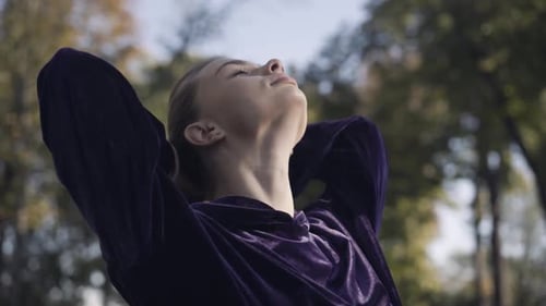Young Woman Tying Hair Back in Autumn Park