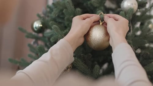 Woman Hanging Ornament on Christmas Tree Close Up