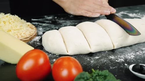 Chef Cutting Pizza Dough on Flour-Dusted Surface