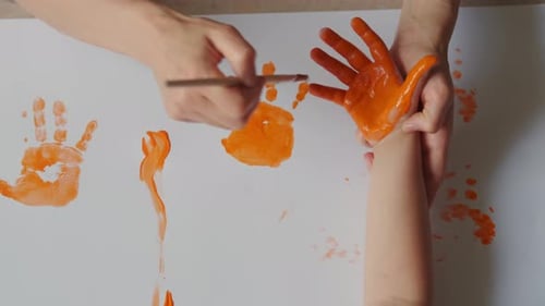 Child Makes Handprints with Paint with Adult Supervision