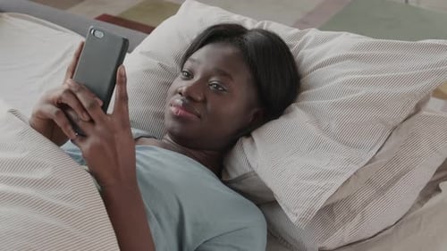 Woman Relaxing in Bed with Smartphone