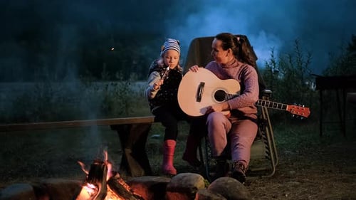 Mother and Child Enjoying Campfire with Guitar