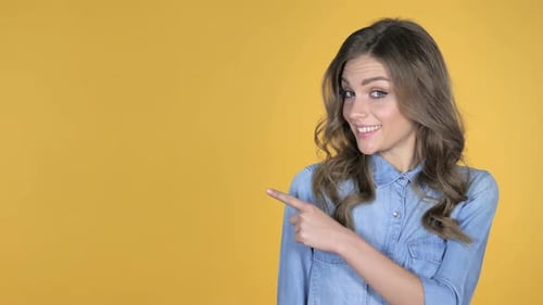 Woman Gesturing to the Left on Yellow Background
