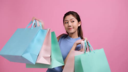 Happy beautiful Asian young woman holding colorful shopping bags