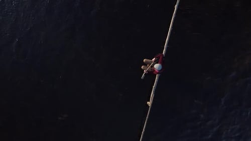 The Guitarist Sits on a Wooden Crossbar in the Middle of a Stream of Water and Plays a Black