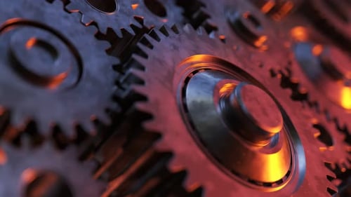Closeup on slowly rotating dark metallic gears. Clockwork machinery in motion.