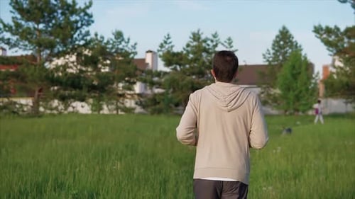 An Adult Male in a Sport Suit Runs Along a Walking Path in Park on a Summer Day