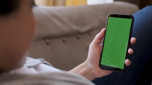 Woman using smartphone watching green screen on mobile phone, online enjoying reading