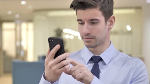 Young Man Using Cellphone in Office Setting