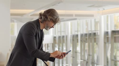 Elegant Man Using Smartphone in Bright Lobby