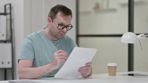 Man Celebrates Good News Reading Documents in Office