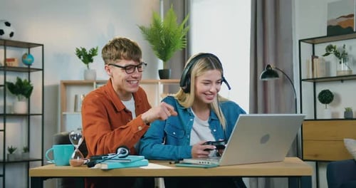 Joven pareja que se alegra de ganar en Vídeo en una computadora portátil y chocar los cinco