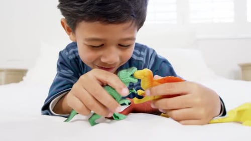 Boy Plays With Dinosaurs on a White Bed