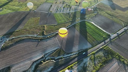Hot air balloons fly over the mountainous landscape of Cappadocia, Turkey.