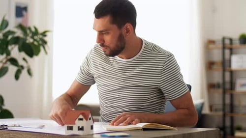 Male Architect with Blueprint Works at Home Office