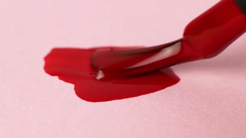 Red Nail Polish Spreading On Pink Surface Close Up