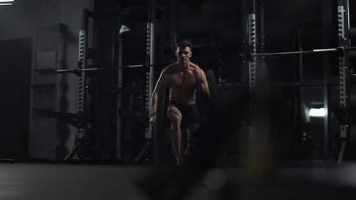 Athletic Man Performs Exercises with Battle Ropes Endurance Training in the Gym Cinematic Light Slow