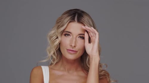 Studio portrait of young and beautiful blond woman over grey background.