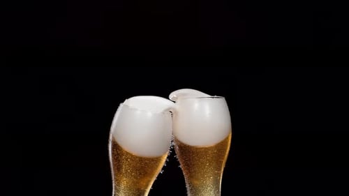 Having a toast with two glasses of beer and spilling. Slow Motion.