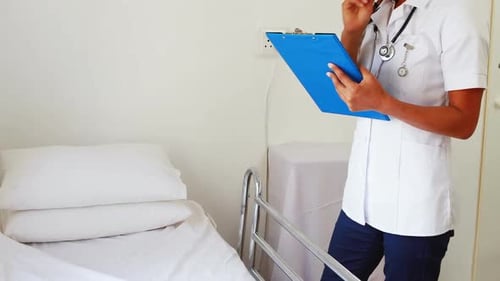 Female doctor with a stethoscope writing on a notebook while standing