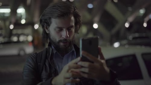 Smiling Man Making Video Call on Smartphone in Night City