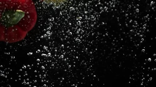 Peppers Splashing in Water on Black Background