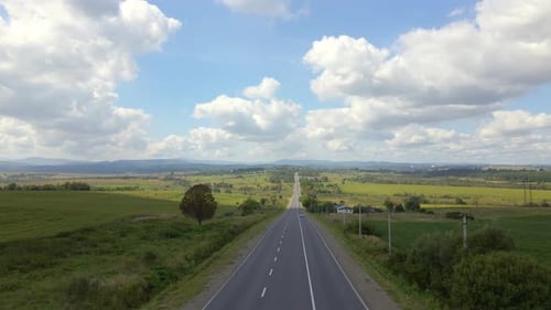 Aerial View of Intercity Road Between Green Agricultural Fields with Fast Driving Cars