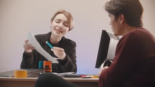 Woman Holding Papers and Telling What Is on Them and Man Is Listening