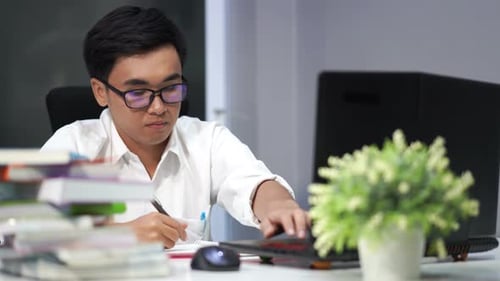 Young Adult Studying at Desk with Computer and Books