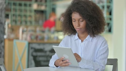 Serious Professional African Woman Using Tablet in Cafe