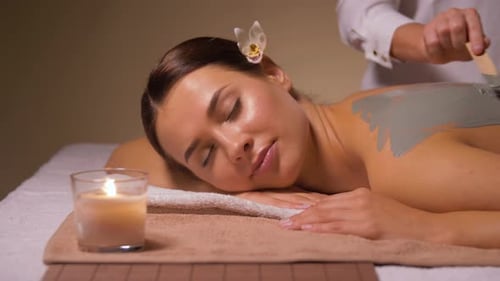 Woman and Cosmetologist Applying Clay Mask in Spa