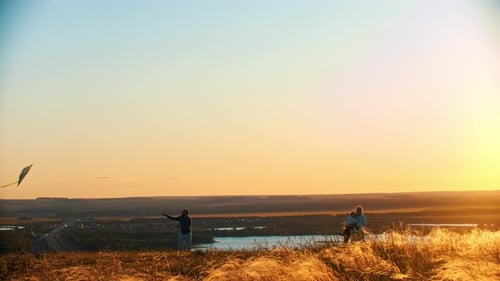 Young Family Playing with Kite on the Wheat Field on Sunset - Father Holding the Rope of Kite