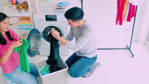 Couple Loading Clothes Into Washing Machine at Home