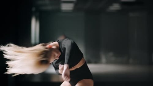 Hot Girl Is Dancing at the Dark Studio Background. Sexy Blonde Woman Is Practicing Dance