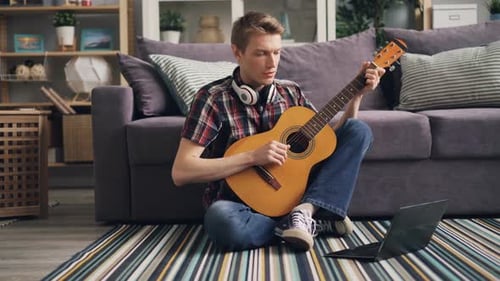 Young Adult Playing Guitar in Living Room
