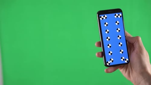 Man Swipes Up and Down the Content on the Mobile in His Hand with Tracking Markers on a Green Screen