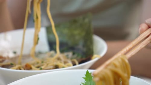 Trendy Greasy Asian Street Food. Close Up of Noodles From Ramen Soups Hanging on the Chopsticks.