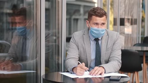 Business Man Wearing Face Mask Working with Papers in Cafe