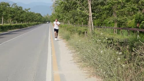 Man Jogging on Roadside Path Near Trees