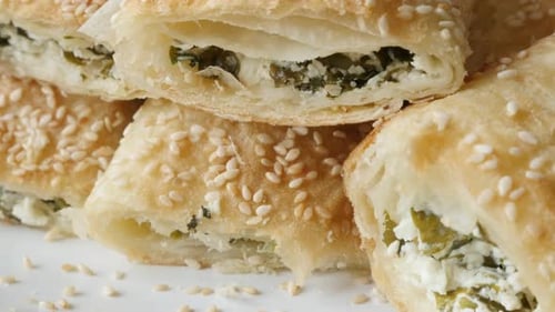 Leckere gefüllte Filo-Kuchen mit Sesamkäse und Spinat, serviert auf Teller 4K 2160p 30fps UHD-Aufnahmen -